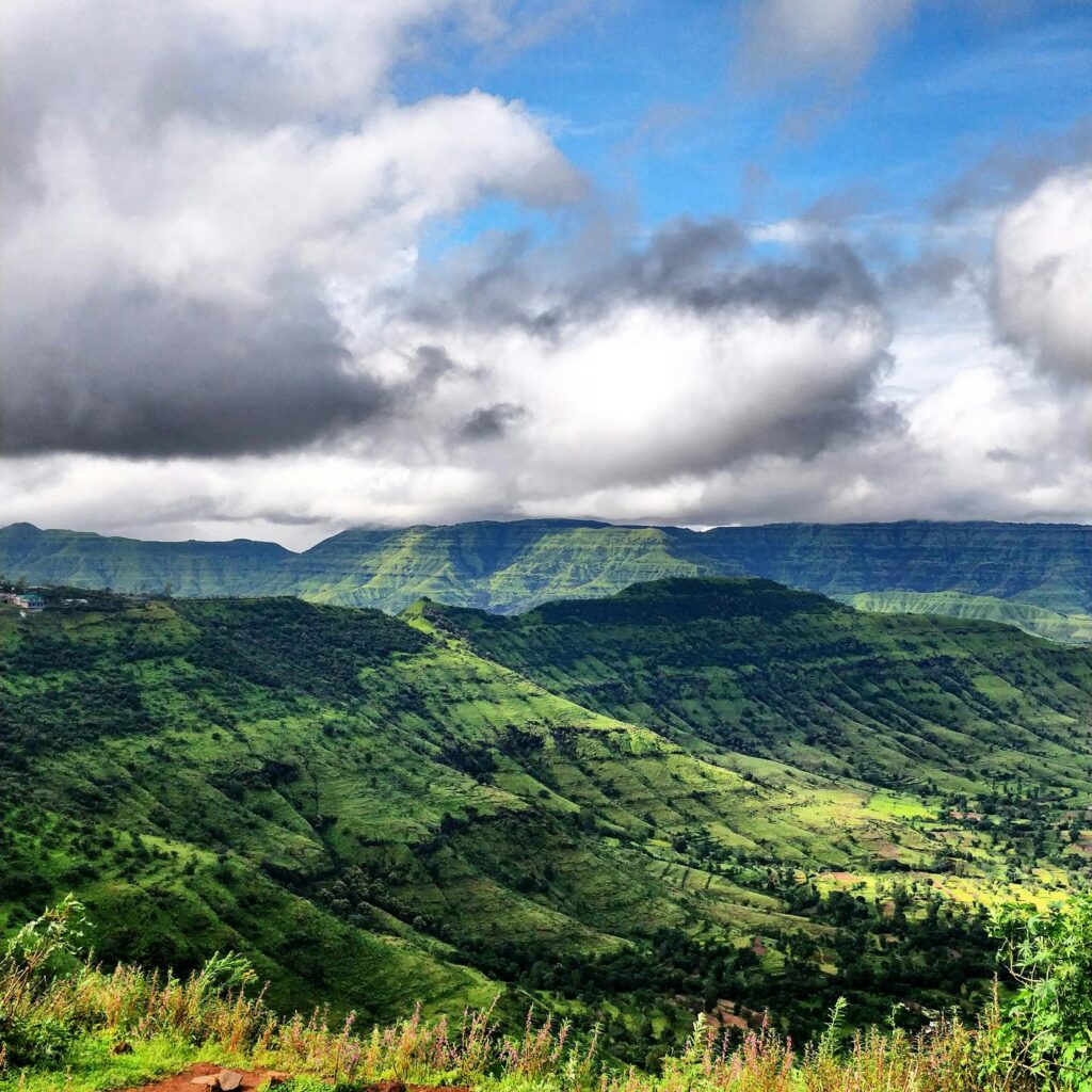 Stunning aerial view of the lush green Panchgani hills under a dramatic cloudy sky.