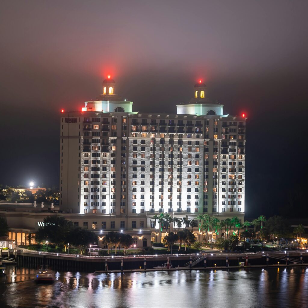 A stunning view of an illuminated hotel reflecting on the water at night, showcasing modern architecture.